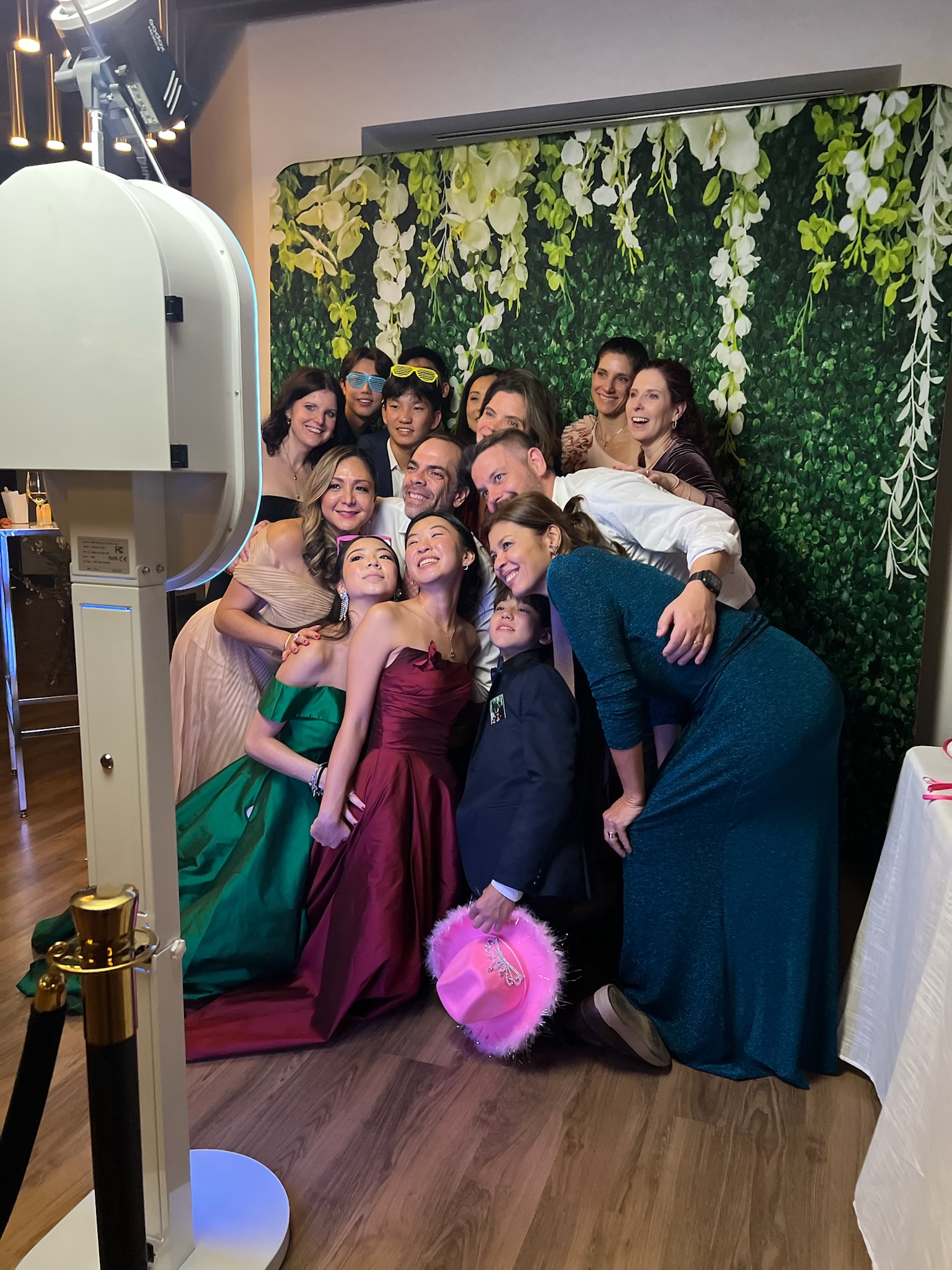 Guests gathered together for a photo at a Grand PhotoBooths flower-wall setup